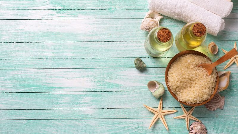 Bath salt, oil and towels on a wooden table